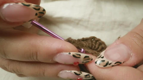 Close-up of a crocheted garment with nails decorated with an animal print Stock Footage 344322202