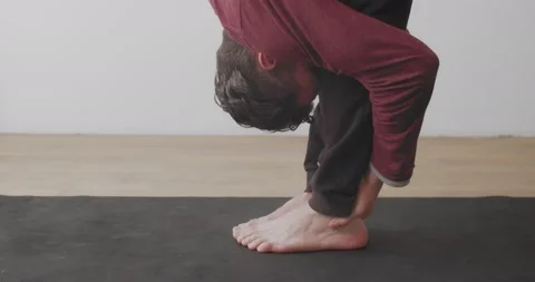 Close up crop view of man stretching legs in uttanasana asana on mat indoors Stock Footage 141246492