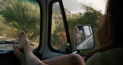 Close crop Woman resting legs on dashboard driving in car on road trip adventure Stock Footage