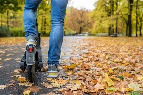 Close-up cropped image of a man on an electric scooter in Autumn Stock Photos