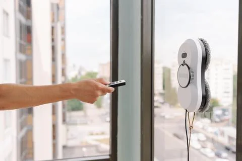 Close-up cropped shot of housekeeper using remote controller to operate robotic Stock Photos