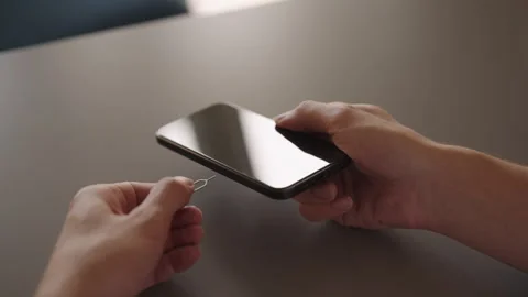 Close-up cropped shot of man using sim ejector tool into smartphone to remove or Stock Footage 321403256