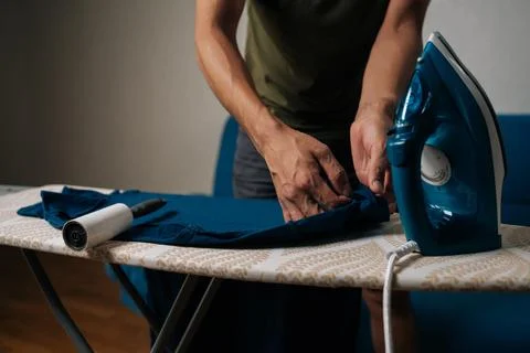 Close-up cropped shot of man using sticky lint roller to remove dust and lint Photos