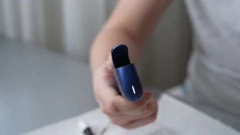 Close-up cropped shot of unrecognizable man holding sleek blue iqos electronic Stock Footage 297954725