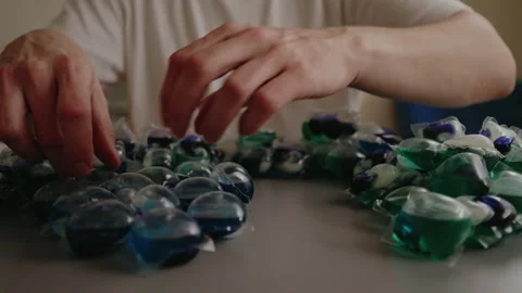 Close-up cropped shot of unrecognizable man sorting colorful laundry detergent Stock Footage 313297891
