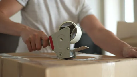 Close-up cropped shot of unrecognizable moving service worker sealing carton box Stock Footage 251582447