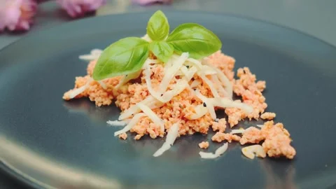 Close-up of crumbled orange dish garnished with basil on black plate indoors Stockbeeldmateriaal 342875420