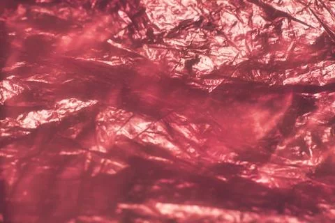 Close-up of crumpled red foil with reflective surfaces, creating abstract p.. Stock Photos