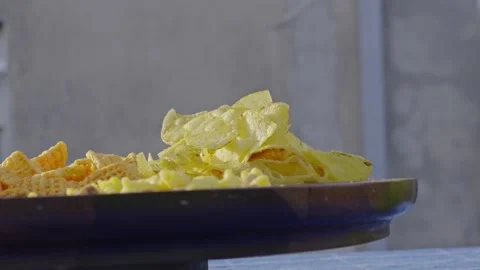 Close-up of Crunchy Potato Chips and Snacks on a Rustic Plate in Natural Light Stock Footage 342578939