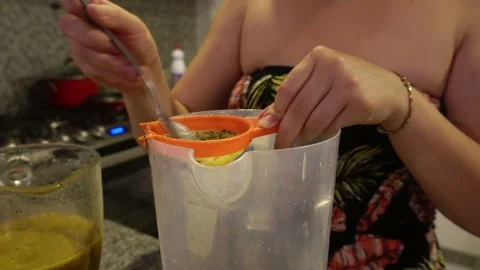Close-up crushing a fruit in a strainer with a spoon to extract the juice on a Stock Footage 193011565