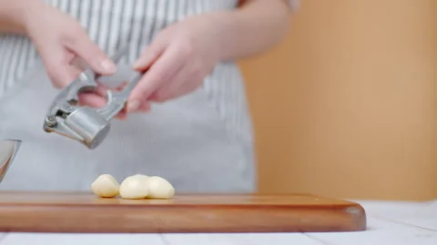 Close-up of crushing large cloves of garlic with a garlic press in 4K. Stock Footage 138055395