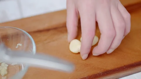 Close-up of crushing large cloves of garlic with a garlic press in 4K. Stock Footage 138055654