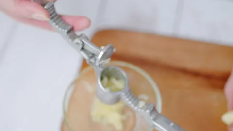 Close-up of crushing large cloves of garlic with a garlic press in 4K. Stock Footage 138057481