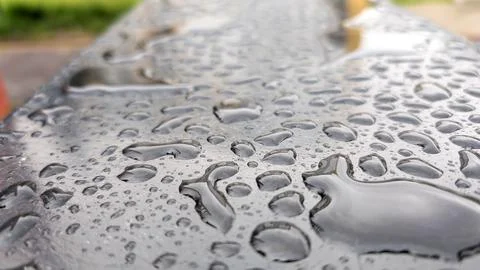 Close Up Of Crystal Clear Rain Drops On Dark Surface Foto stock