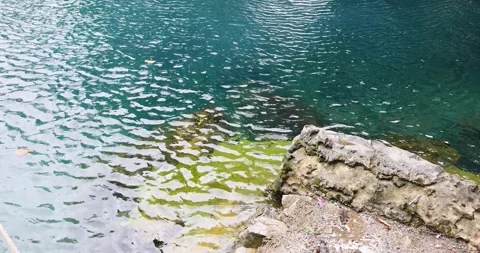 A close-up of the crystal-clear water surface  blue-green near the rocks. Stock Footage 314886164
