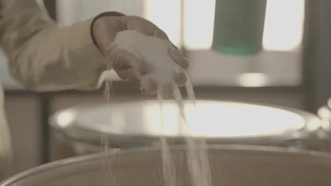 Close-up of crystalline white powder falling from a hand into a vat Stock-Footage 327633019