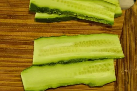 Close up of a cucumber cut into thin slices to be used on a hamburger Stock Photos