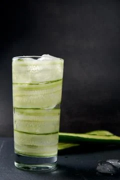 Close up of cucumber water with ice in a tall glass on a dark background Stock Photos