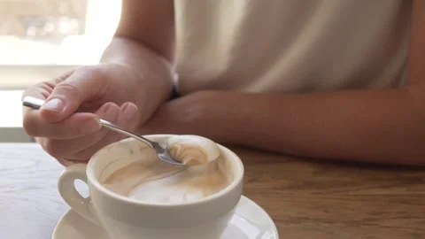 Close-up of a cup of cappuccino on a table next to a woman. Stock Footage 249052605