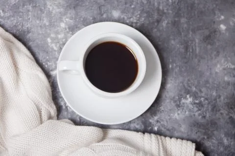 Close up of cup of coffee and knittead white plaid on the gray background Stock Photos