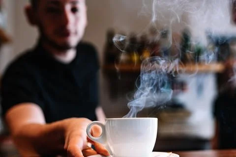 Close-up of a cup of coffee on a bar counter. Waiter serving coffee at the Stock Photos