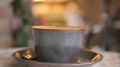 Close-up of a cup of coffee on a table in a cafe, steam rising slowly from .. Stock Footage 332744559