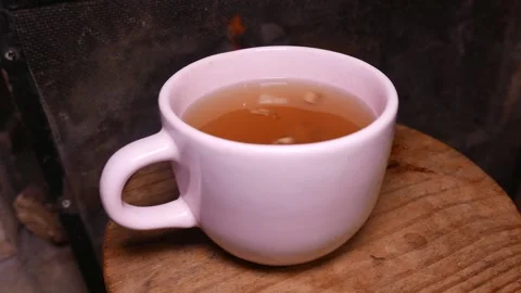 Close-up of a cup of ginger and honey tea on a table in front of a fireplace Stock Footage 335181318