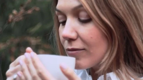 Close-up of a cup with hot tea or coffee in the hands of a young girl Stock Footage 82499972