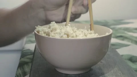 Close up of cup of rice and hands holding chopsticks Stock Footage 134069528