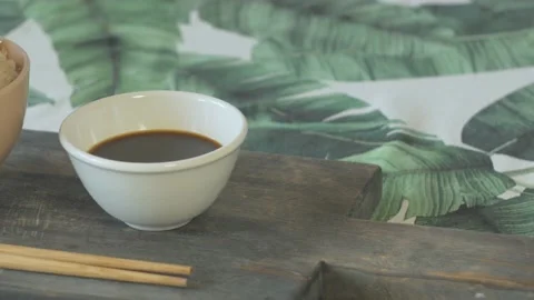 Close up of cup of rice cup of soy sauce and chopsticks with leaves background Stock Footage 134069531