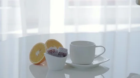 Close-up of a Cup of tea and marmalade on a white table. Woman pours tea Stock Footage 92376449