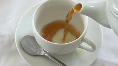 Close up of a cup of tea being poured from a white tea pot and adding milk Stock Footage 65859737