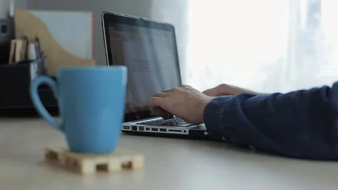 Close up of cup of tea or cofee against male hands typing on a laptop on the Stock-Footage 104425849