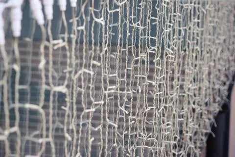 Close-up of a curtain of string lights with a blurred brick wall background.. Stock Photos