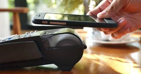 Close-up customer hand uses smartphone to make a wireless payment nfc technology Video stock 336585670