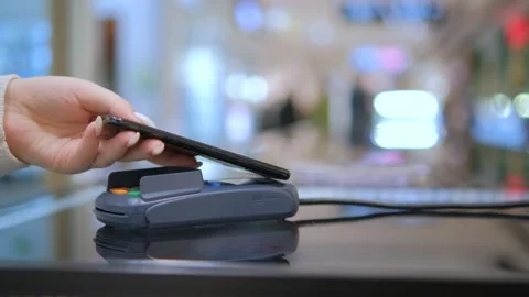 Close up customer paying with an NFC contactless smartphone with a card machine. Видео 232611521