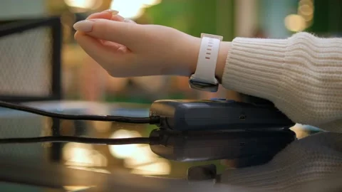 Close up customer paying with an NFC contactless smartwatch with a card machine. Видео 232705710