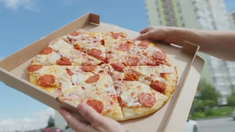 Close up of customer receiving hot pepperoni pizza outdoors on city background Stock Footage 345203308