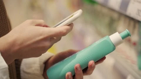 Close-up customer using a smartphone to scan a QR code on a shower gel package Stock Footage 173030587