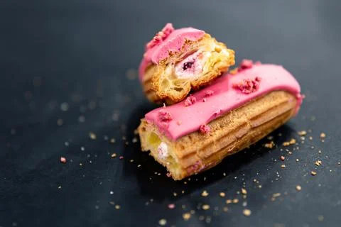Close-up of a cut berry eclair on a black background. Stock Photos