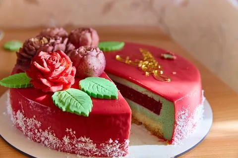A close-up cut of a berry vanilla mousse cake with edible flowers Stock Photos