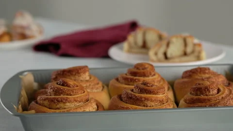 Close-up cut of cinnamon rolls on a plate. Sweet cream cheese frosting pouring Stock Footage 141374724
