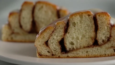 Close-up cut of cinnamon rolls on a plate. Sweet cream cheese frosting pouring Stock Footage 145090215