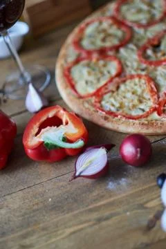 Close-up of cut half of red pepper, onion and circle cooked pizza. Stock Photos