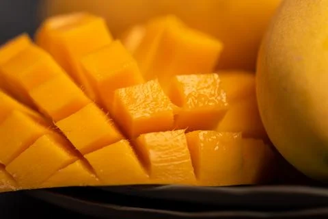 Close up of cut mango pieces against a dark background Stock Photos