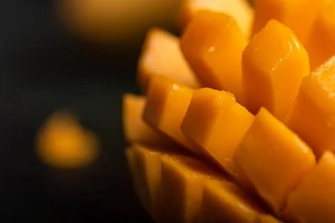 Close up of cut mango pieces against a dark background Stock Photos