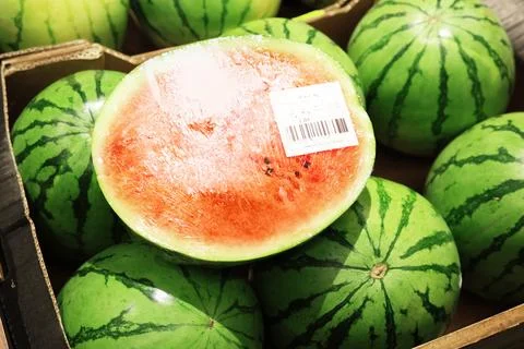 A close-up of a cut watermelon half wrapped in plastic with a barcode label.. Foto stock