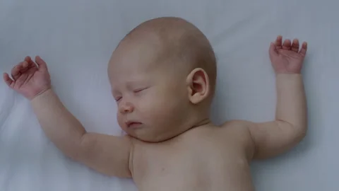 Close up, cute, beautiful, innocent newborn baby sleeping sweetly in bed Stock Footage 306042812