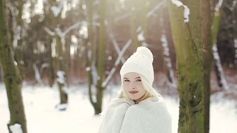 Close-up of a cute blonde woman with blue eyes in a winter forest fixes a Vidéo 85242453