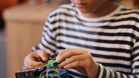 Close up of cute boy in striping sweater assembling a robot parts in the modern Stock Footage 82492819